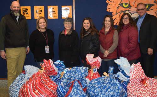 OFAC Visual Credit Union employees and school officials stand with bags of coat donations